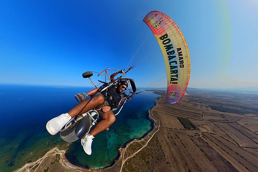 Volo tandem in paramotore sopra la costa del Sinis in Sardegna con vista panoramica sul mare