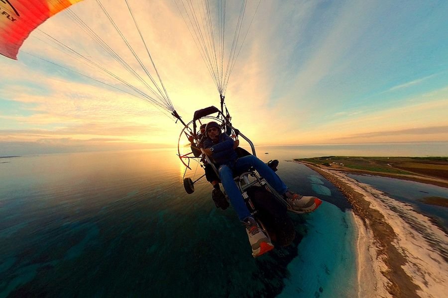 Volo in paramotore tandem al tramonto sopra il mare cristallino della penisola del Sinis in Sardegna